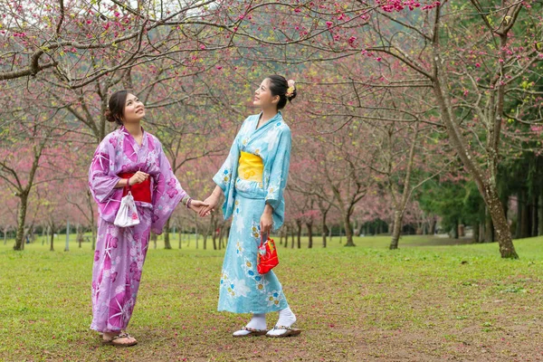 İki Asyalı kadın yan yana ve tutan eller yan yana ve gökyüzüne bak.