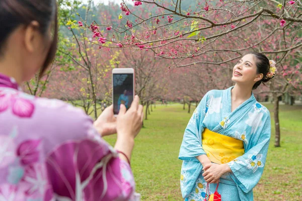 Asya genç bayanlar birbirlerine karşılıklı onların bellek kaydetmek için smartphone kullanarak fotoğraf çekmek yardımcı.