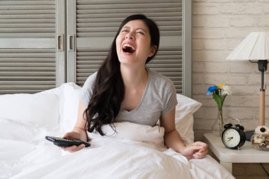 Kahkaha içine Asya kadın oturma yatak ve patlama. Gerçekten yüksek ruhu içinde bir kız.