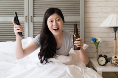 Asyalı kadın uzaktan kumanda ve bira şişesi onun elinde tutan. Onun en sevdiğim beyzbol oyuncusu için bir zafer zafer için çok neşeli kız.