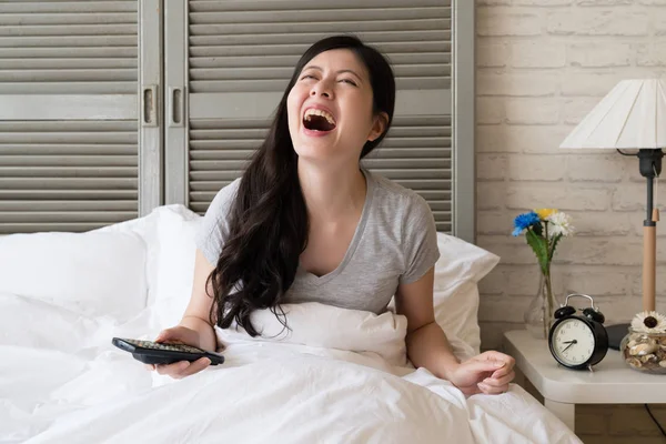 Kahkaha içine Asya kadın oturma yatak ve patlama. Gerçekten yüksek ruhu içinde bir kız.