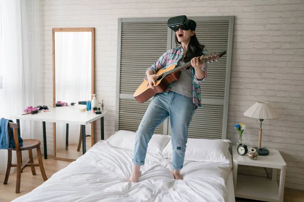 Asyalı kadın gitar video oyun eğlenceli ve heyecan ile oynarken Vr aygıt kulaklık takmış.
