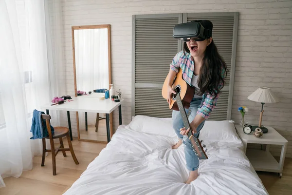 Asyalı kadın kendini müzik konserinde ahşap gitar çalmak Imaging Vr aygıt giyiyor.