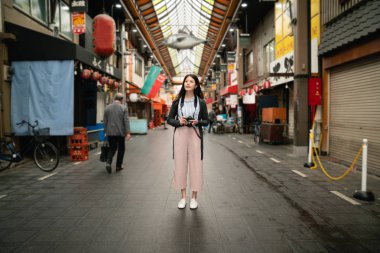 Eski sokak piyasada ayakta Asya ziyaretçi. Japonya arka tarafından. bir kamera tutarak.