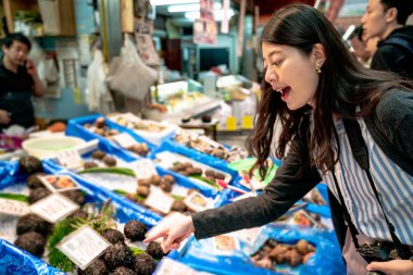 Güzel Asyalı kız taze yiyecek aramaya. piyasada arka tarafından.