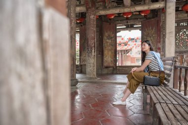 Asyalı kadın bankta oturan yan görünüm.