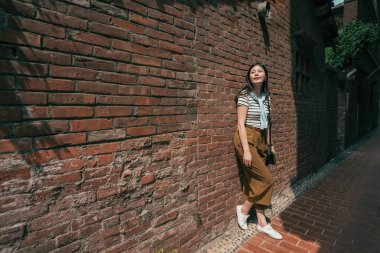 duvara yaslanmış güzel kadın. Eski sokağın ortasında duran.