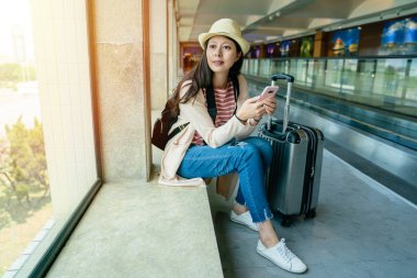 üstünde belgili tanımlık pencere mobil tutarak ve adımımızı görünümüyle tarama ve rahatlatıcı oturan prety Asyalı kadın.