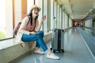 gülüyor ve üstünde belgili tanımlık pencere oturan Asya ziyaretçi. belgili tanımlık hareket eden holding. rahatlatıcı ve zevk görünümü.