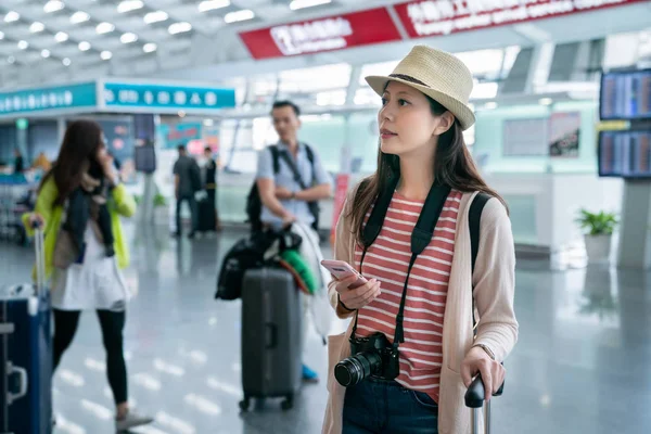 beklerken bir şey kontrol ziyaretçi. akıllı telefon elinde tutuyor. havaalanında mağazalar arka tarafından. 