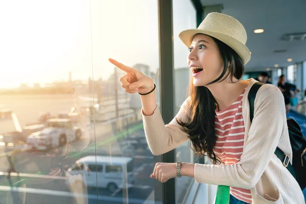 büyük pencerelerde eğilerek Asya ziyaretçi. duygu neşeli ve işaretleme bir yere at. Yarım vücut görünümü.