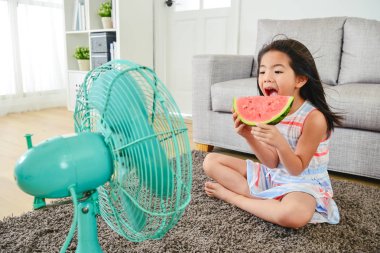 lovely girl eating melon with a big bite. sitting in front of a fan with legs crossed. cooling herself down from heat. clipart