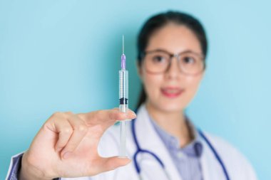 Enjeksiyon izole mavi bir arka plan ile kadın bir doktor tarafından tutarak bir elinde yakın çekim.