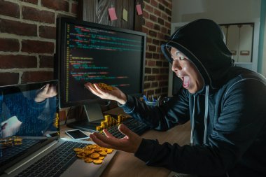 Erkek hacker soygun fidye için mutlu bir şekilde gülerek. bitcoin onun elinde bir yığın kapma. 