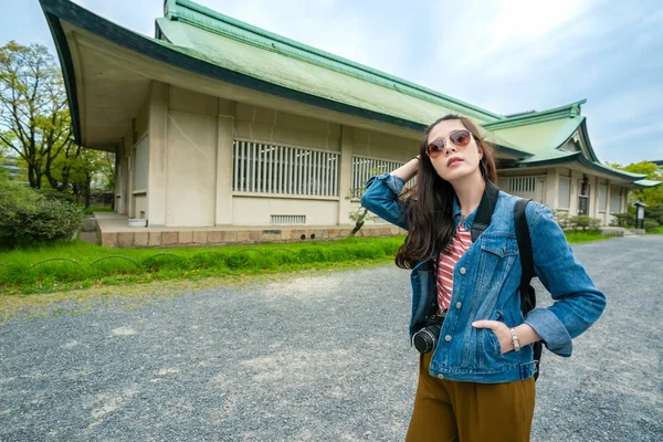 poz ve osaka Kalesi güneşli mavi gökyüzü ile gezi sırasında cebinde el koyarak fashinable travle kadın.