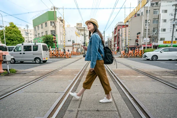 Japonya'nın osaka şehrinde onun telefon tutarak demiryolu boyunca yürüyen rahat seyahat kadın.