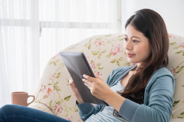 güzel genç erkek ile bir enjoyful bakmak oturma odasında kanepede oturan tablet okuma.