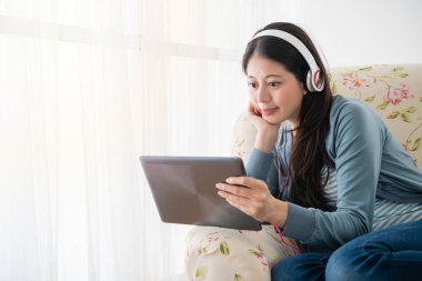 kadın oturma odasında kulaklık giyerek tablet ile bir el holdig yüz okuma.