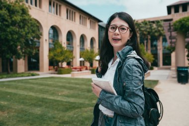 female international student looking happily and heading to her classroom. clipart