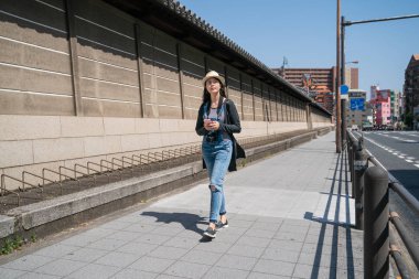 Osaka diğer tarafta tapınak duvarları ve sokak tarafından yürüme çekici travle kadın.