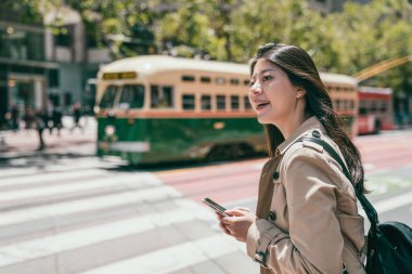 çekici bir genç kız yol geçtikten için beklerken smartphone holding yan görünüm.