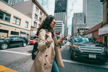 Genç profesyonel kadın onun cep kullanırken yol geçiş ne zaman telefon bekleyen arabalar.