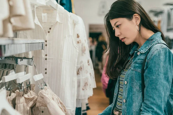 stock image pretty young asian woman browsing and choosing clothes in a ready to wear store.