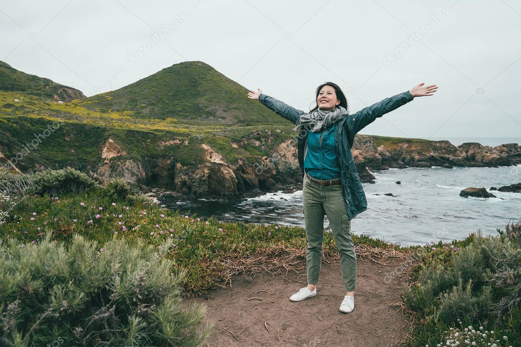 travel woman opening her arms to embrace the nature standing on the brilliant and beautiful coast.