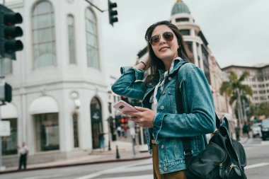 kendine güvenen bayan saçları ve ayakta Rodeo Drive'da hareketleri ve alışveriş gidiyor