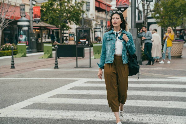 элегантная женщина переходит дорогу, она выглядит расслабиться, потому что сегодня ее праздник, она собирается по магазинам
