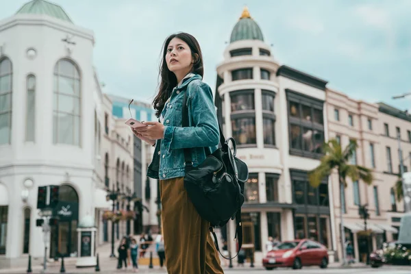 Beverly Hills yolda duran ve cep telefonuyla doğru yön bulma zarif kadın