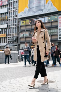 sokakta yürürken, yüksek topuklu giyen ve pembe bir cep telefonu tutan bir kadın uzun boylu moda