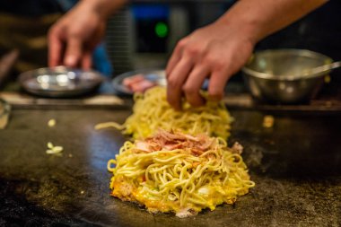 Şef Okonomiyaki demir plaka üzerinde yemek, erişte Okonomiyaki, lezzetli Japon geleneksel yemek yapıyor