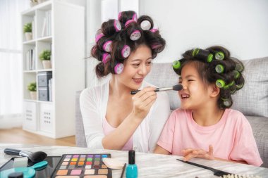 güzel anne şirin kızının yüz fırça ile boyama neşeyle oturma odasında görünüyorlar