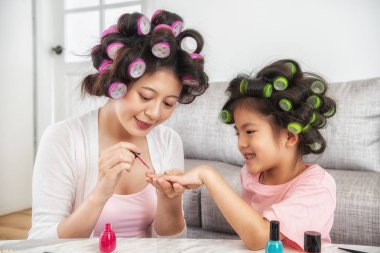 Onu daha mutlu ve daha güzel yapmak için anne pembe oje şirin kızının çivi boya kullanarak