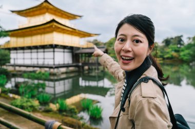çok kadın Gezgin Kamera ve gülümseyen Kinkakuji Tapınağı yüze işaret. Japonya'nın Kyoto gezi. Backpacker yaşam tarzı.