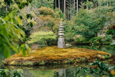 Japon fener ayakta orman gölette ortasında taş. Kyoto Japonya'da doğa kavramı. huzurlu bir yeşil park bulunan geleneksel taş heykel.