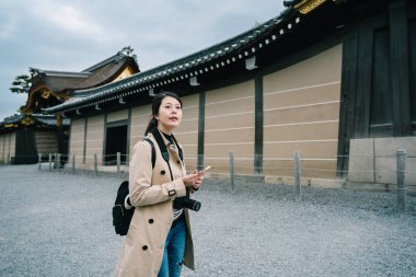 tapınakta duran ve arkadaşlarıyla iletişim kurmak için smartphone kullanarak güzel gezgin kim hala tapınak içinde ziyaret etti. soğuk havalarda bekleyen kadın. Japonya kavramında gezi.