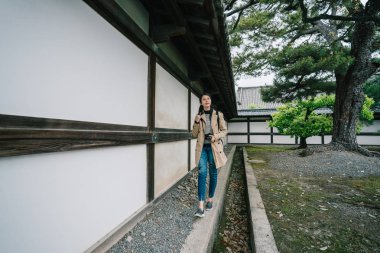 tam uzunlukta fotoğraf güzel bir kadın gezgin sevinçle tapınak içinde yürüyüş. yeşil bahçe ile soğuk havalarda taş yollar. Turizm fotoğrafçı yaşam tarzı.
