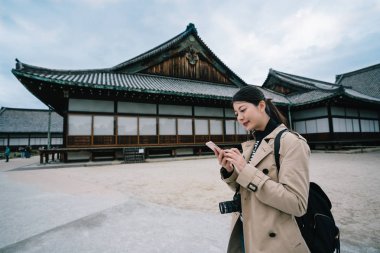 güzel kadın gezgin Tapınağı ziyaret etti ve onun smartphone sonraki yerinde kontrol bitti. Zarif Bayan onu gezisi cep hesap makinesi tarafından Japonya'da maliyet sayma. bahar tatil kavramı içinde seyahat.