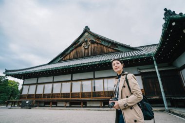ünlü Japon tapınağın gezi zarif turist onun kamera tutarak. Japonya'nın Kyoto seyahat. kadın backpacker bahar yalnız Japonya'da ziyaret.