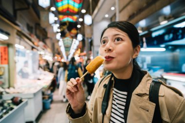 çok kadın backpacker gülümseme sevinçle çünkü lezzetli Oden onu şaşırtmış. Gezgin lezzetli Japon geleneksel snack çalışıyor. bahar tatil Japonya.