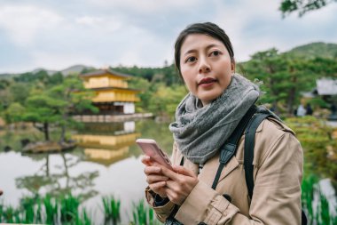 diğer Kinkakuji temple içinde belgili tanımlık geçmiş ile aramaya gölet yakınında duran zarif kadın. Japonya'da tatil genç kadın gezgin.