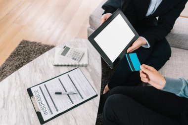 iş kadını ve sigorta dava ile anlaşması olan istemci. müşteri kredi kartı ile ödeme yapıyor. hesap makinesi ve evde masa üzerindeki belgeler.