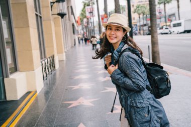 hasır şapka giyen ve sevinçle sokakta yürüyen kadın seyahat. Genç backpacker yüz kamera gülümsüyor heyecan verici. çekici Bayan ABD tatil sırasında alışveriş mutlu bir yaşam tarzı yaşam.