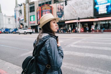 yolun karşısına için bekleyen bir sırt çantası taşıyan kadın gezgin. Los Angeles'ta sokakta tatil ayakta backpacking üzerinde genç kız mutlu. Bizi Hollywood Turizm.