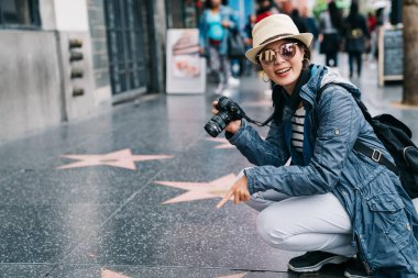 kadın fotoğrafçı sevinçle yere yıldız işareti resim çekmek. Hollywood Bulvarı'nda ünlü dönüm noktası. Amerika yaz tatil kız şehir zevk seyahat.