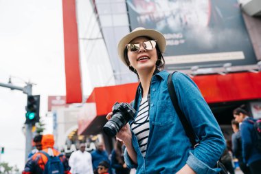 çekici kadın fotoğrafçı meşgul sokak ve alarak resmi halk için ayakta. güzel genç kız DSLR kamera tutarak. seyahat objektif kadın yaşam tarzı.