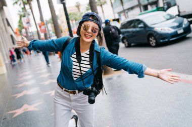 sevinçle kollarını açarak ve Hollywood Bulvarı'nda duran kadın turist. Şehir zevk La seyahat bize yaz tatil kız sokakta kaygısız Asya Bayan.