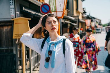 zarif gezgin kafasını Japonya'da hostel için doğru şekilde düşünmeye süre dokunaklı. kimono arka planda yürüyen iki genç kız. Kyoto Japon yaşam tarzı.